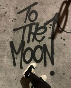 a person standing in front of a wall with the words to the moon written on it