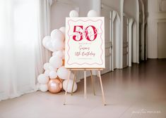 a 50th birthday sign sitting on top of a wooden easel next to some balloons