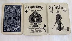 three playing cards are sitting on a white tablecloth, one is blue and the other has black ink