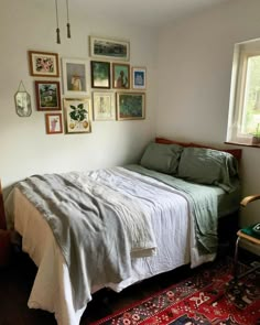 a bed sitting in a bedroom next to a window with lots of pictures on the wall