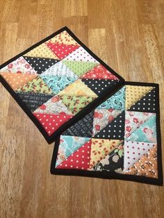 two quilted placemats sitting on top of a wooden floor