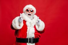 a man dressed as santa claus giving the thumbs up sign with his hand on a red background