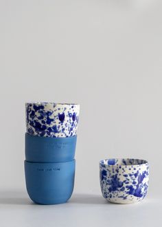 two blue and white cups sitting next to each other on top of a gray surface