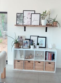 a white shelf filled with pictures and plants