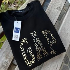 a black t - shirt with leopard print on it sitting on a wooden park bench