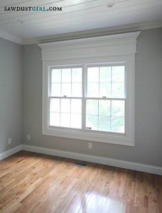 an empty room with hard wood floors and white trim on the windows, painted gray