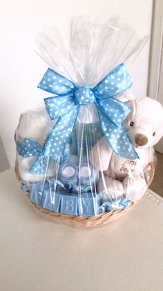 a teddy bear sitting in a basket with blue ribbon and white polka dots on it