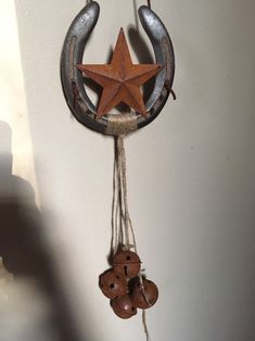 a wooden star hanging from the side of a wall with two bells attached to it