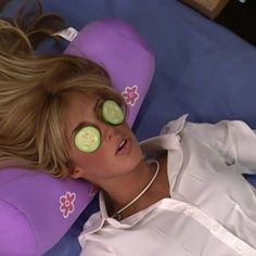 a woman laying down with cucumbers on her eyes