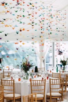 a room filled with lots of tables and chairs covered in paper cranes hanging from the ceiling