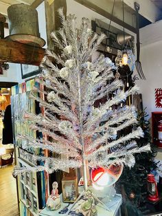 a white christmas tree sitting on top of a table next to a pile of books