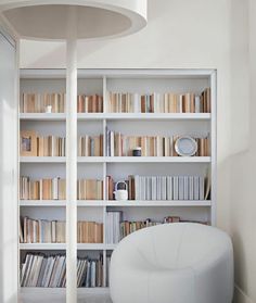 a white chair sitting in front of a bookshelf filled with lots of books