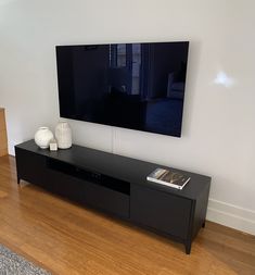 a flat screen tv sitting on top of a black entertainment center in a living room