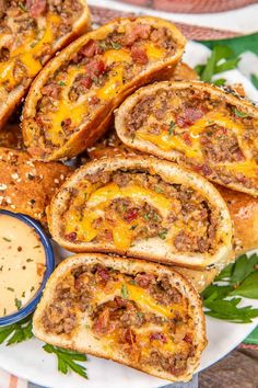 several pieces of bread with meat and cheese on it sitting on a plate next to a small bowl of dipping sauce