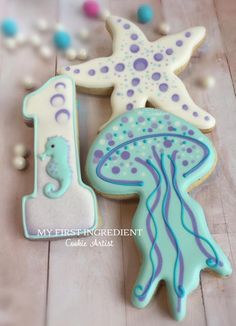 two decorated cookies sitting on top of a wooden table next to sea animals and beads