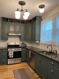 a kitchen with green cabinets and stainless steel appliances, including an oven, dishwasher, sink, and stovetop