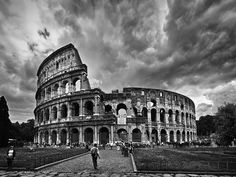 black and white photograph of the colossion in rome, italy with people walking around