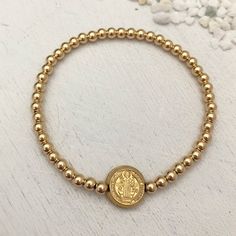 This classic piece is a jewelry lover's must have! Sure to become your new favorite everyday staple. 3mm quality gold fill beads strung on super strong stretch cord. 11mm double sided St Benedict coin charm. Perfect for creating layered looks or wear one alone. Dating back over 1,000 years, the Benedictine cross is one of the most powerful symbols of divine protection in the Christian world. Carry this cross with you at all times as a symbol of protection over you, your loved ones and all of you Gold Stackable Stretch Bracelet, Gold Single Strand Spiritual Bracelet, Adjustable Gold Jewelry With 8mm Beads, Adjustable Gold Single Strand Beaded Bracelet, Adjustable Gold Stretch Bracelet For Everyday, Spiritual Gold Charm Bracelet Hypoallergenic, Adjustable Gold Stretch Bracelet Stackable, Adjustable Gold Stretch Bracelet Hand-strung, Stackable Gold Stretch Bracelet