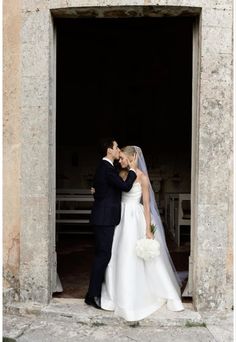 a bride and groom kissing in front of an open doorway