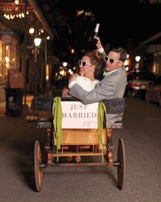 a man and woman are riding in a horse drawn carriage down the street at night