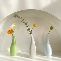 three different colored vases with flowers in them