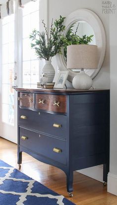 a blue dresser with two vases on top and a mirror above it in the corner