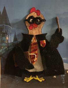 a stuffed chicken dressed in a harry potter costume and holding a wand with both hands