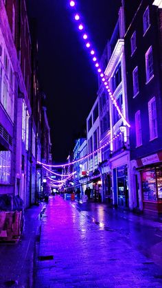 an empty city street is lit up with purple lights