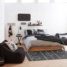 a bed room with a neatly made bed next to a black and white soccer field rug