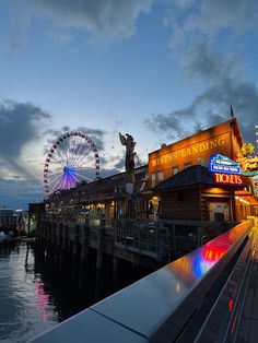 an amusement park next to the water at night