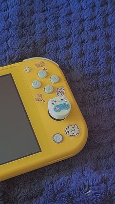 a yellow nintendo wii game system sitting on top of a blue blanket next to buttons