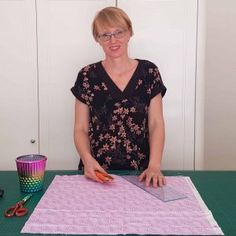 a woman cutting fabric with scissors on a table