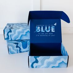 two blue boxes sitting next to each other on a white surface with one open and the other closed