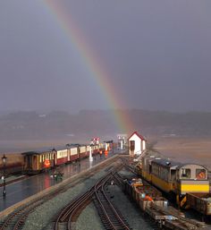 a rainbow is shining in the sky over a train yard with tracks running parallel to each other