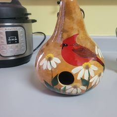 a vase with a bird painted on it sitting next to an instant pressure cooker