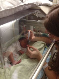 a woman brushing the teeth of a baby in a crib