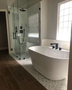 a large white bathtub sitting in the middle of a bathroom next to a walk in shower