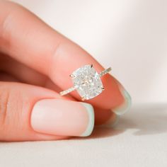 a woman's hand holding an engagement ring with a diamond in the middle, on top of her finger