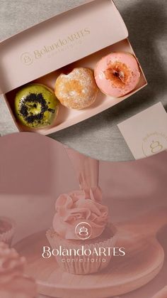 three donuts are in a pink box on a table with the logo behind them