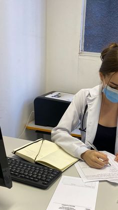 a woman sitting at a desk wearing a face mask