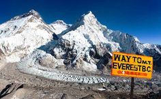 a yellow sign that says way to the everest bc in front of some snow covered mountains