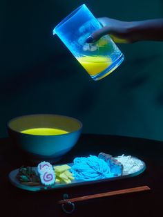 a person is pouring liquid into a bowl with food on it and chopsticks