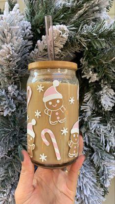 a hand holding up a mason jar decorated with gingerbreads and candy canes