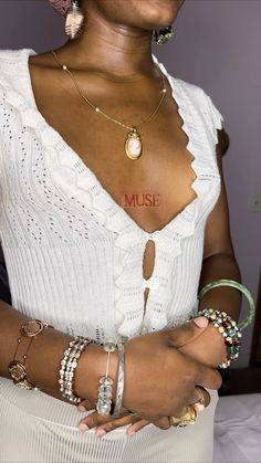 a woman wearing bracelets and a white top with the word muse written on her chest