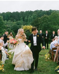 a bride and groom walking down the aisle after their wedding ceremony with guests in the background