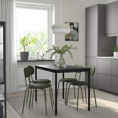 a dining room table and chairs with plants in the middle, near a kitchen window