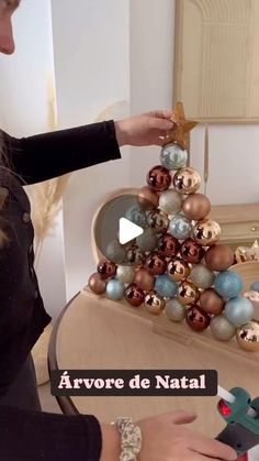 a woman is decorating a christmas tree with baubles and other ornaments on it