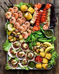 an assortment of seafood on a platter with corn, shrimp, and avocado