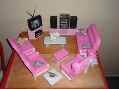 a living room with pink couches, chairs and a tv on top of a wooden table