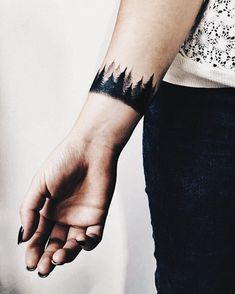 a woman's arm with a tattoo on it that has mountains in the background